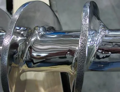 Stainless steel conveyor screw flight finished with the Harrison C-75 process showing the mirror product-release surface